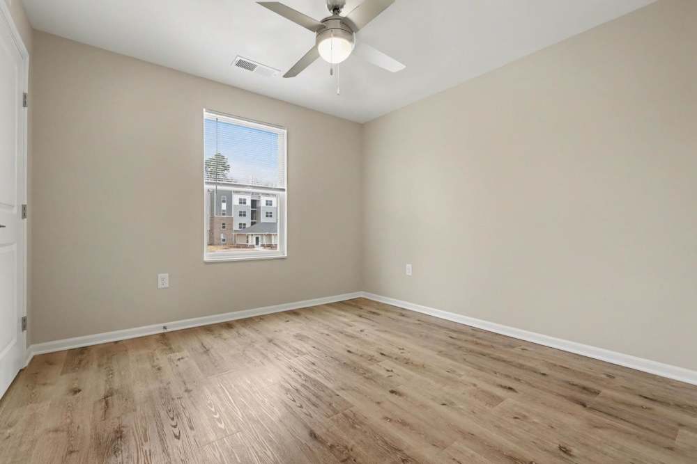 Empty bedroom with wood-style flooring, ceiling fan, and natural light from window at Leonard Greene in Dallas, North Carolina