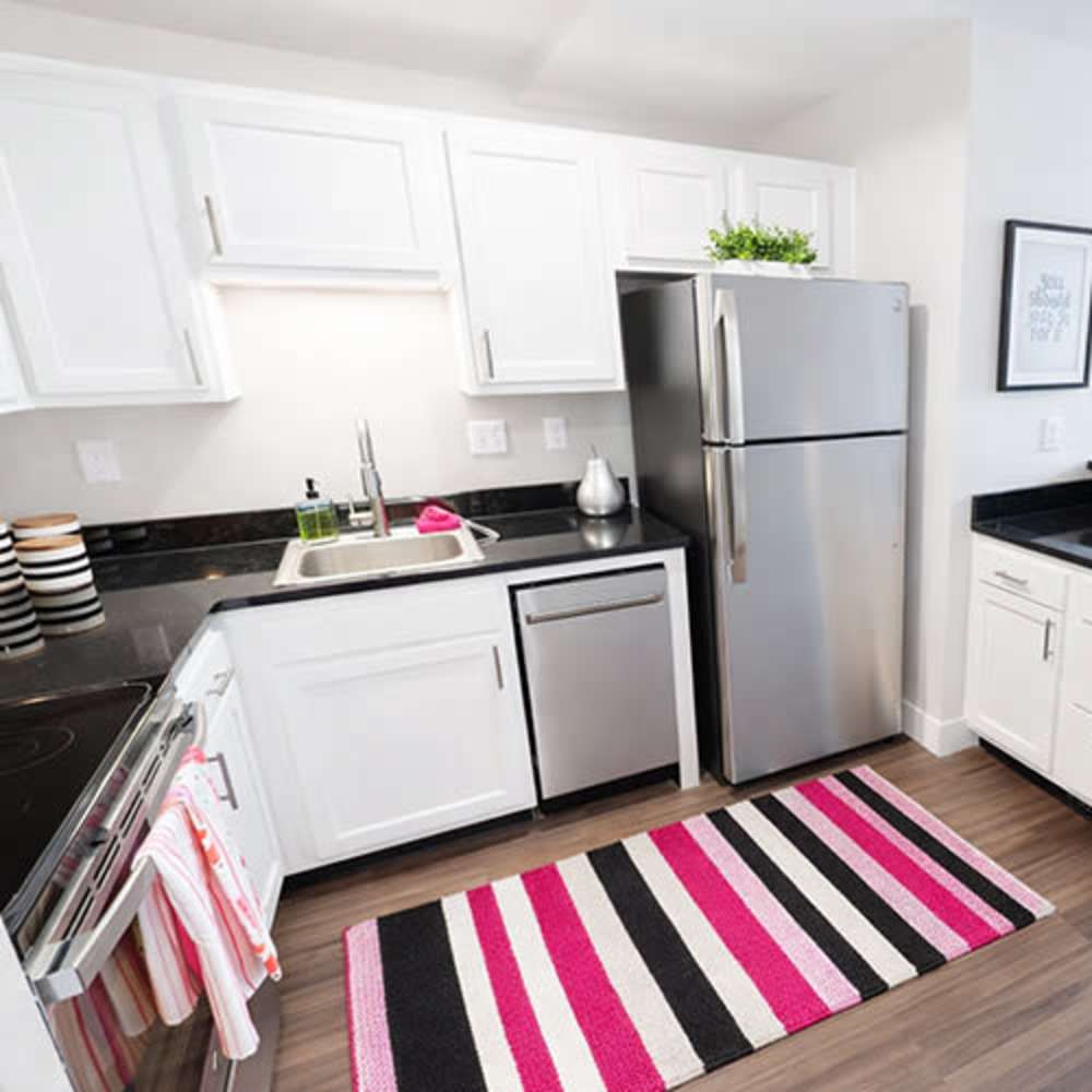 Modern kitchen with granite countertops, stainless steel appliances, and wood-style flooring at Flats on Fifth in Louisville, Kentucky
