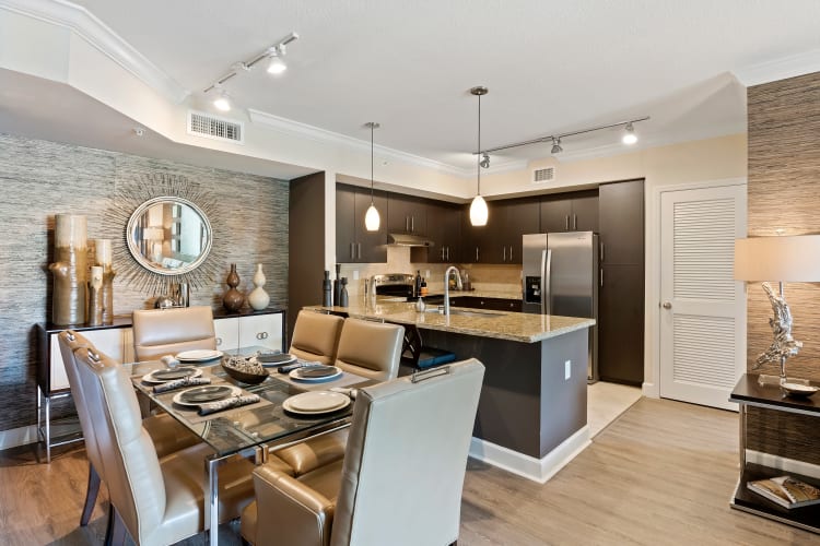 Model dining room and kitchen with stainless-steel appliances and granite countertops at The Residences at Lakehouse in Miami Lakes, Florida