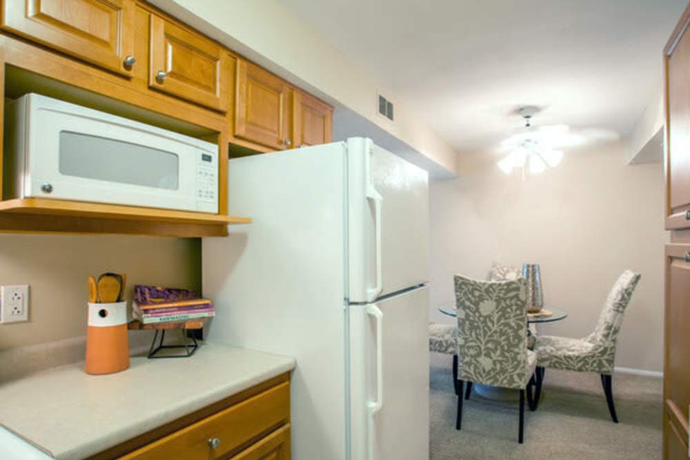 Kitchen with white appliances and view of dining area at Beau Jardin Apartments in St. Louis, Missouri