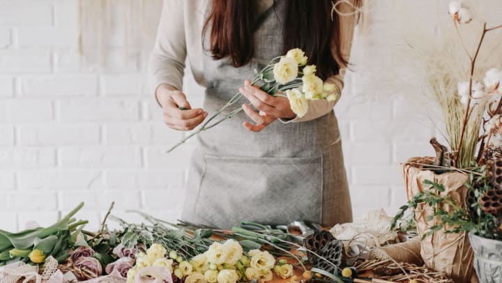 Woman florist collects bouquet from a variety of flowers
