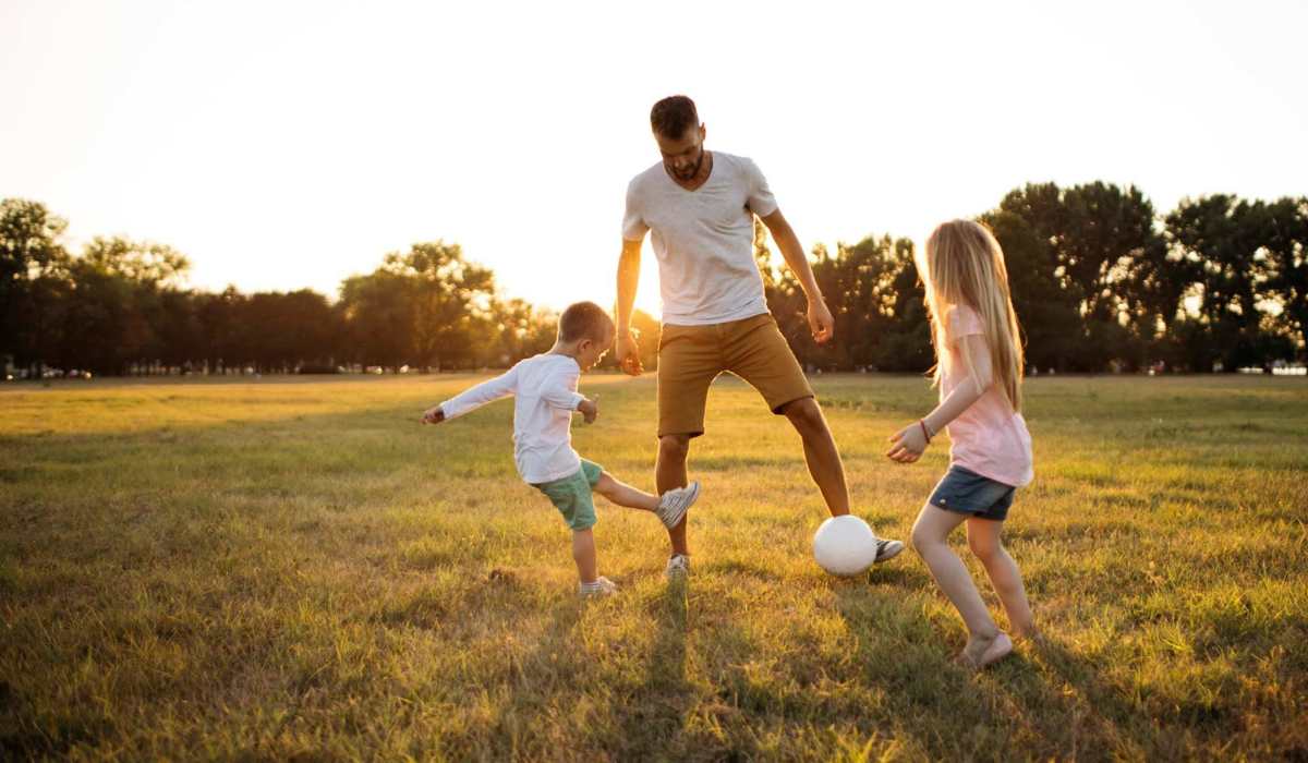 Resident playing football with his chidren at Pine Cove Apartments in Oregon, Wisconsin