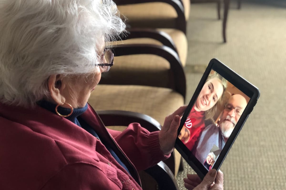 A resident using a tablet to communicate with her family safely at Oxford Glen Memory Care at Sachse in Sachse, Texas