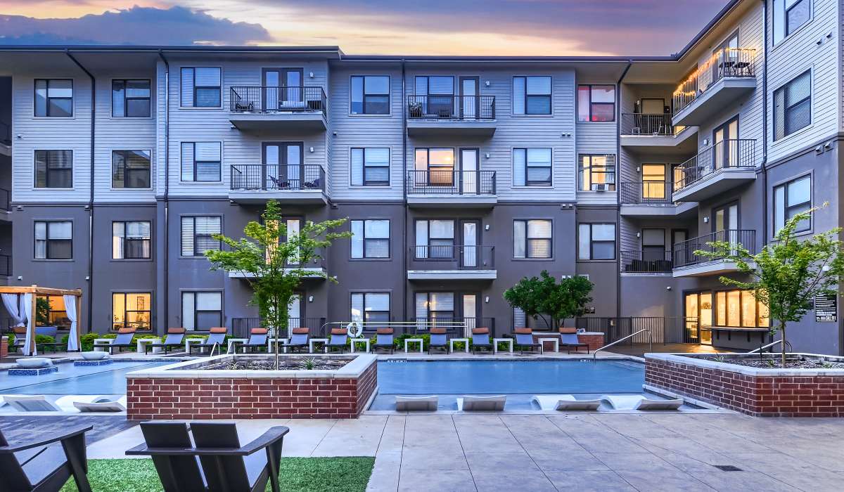Premium community pool with multiple lounge chairs for relaxation by the pool at Factory Design District in Dallas, Texas