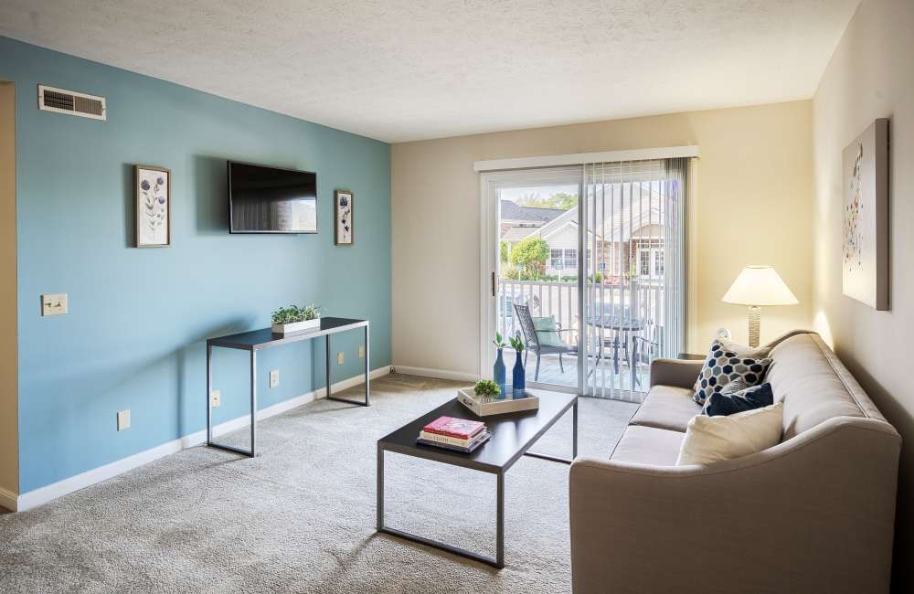 A cozy living room with modern flat screen television and connected to private balcony at Reserve at Ft. Mitchell Apartments in Ft. Mitchell, Kentucky