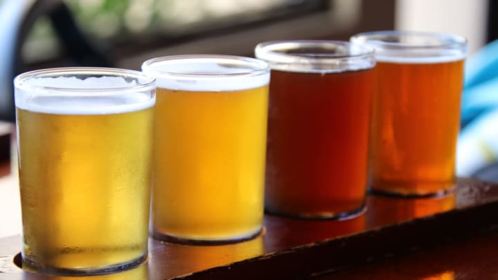 A sample flight of beer arranged on a serving tray with four samplers ranging from a light-colored pilsner to a deep red ale