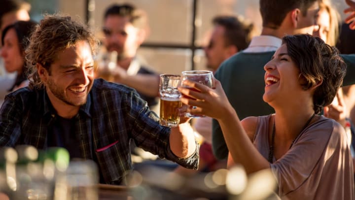 two people drinking beer and laughing at a crowded bar | bars in The Woodlands