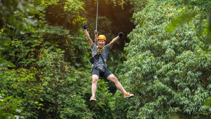 man with hands up while ziplining at AWOL adventure sports