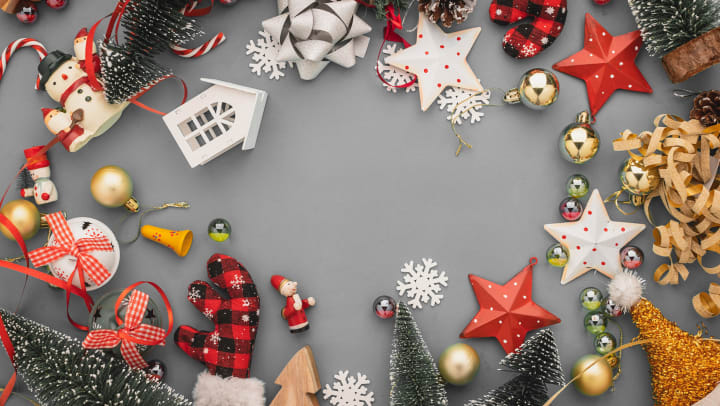 Ornaments and holiday tree decorations spread out on a gray background. 
