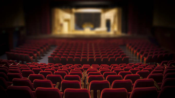 A theater filled with red seats and a lit stage | entertainment near Keller