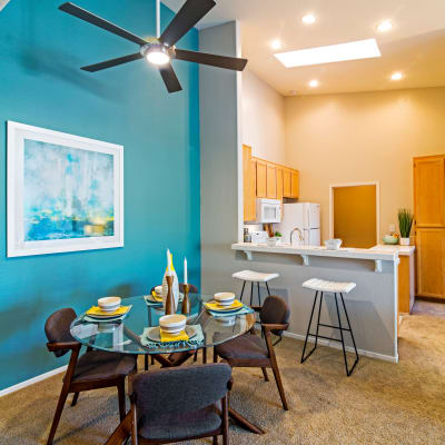 Dining area with an accent wall looking over the breakfast bar into the kitchen of a model home at Sofi Canyon Hills in San Diego, California