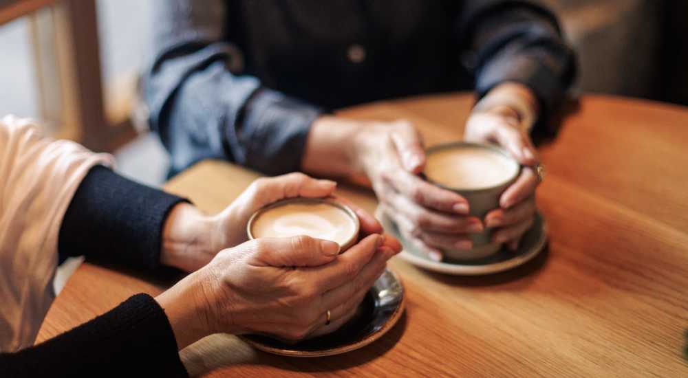 Cozy cafe setting with two people holding coffee cups near August Friendswood in Friendswood, Texas