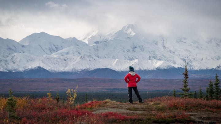 Person standing out in the wilderness looking at a vast mountain range.