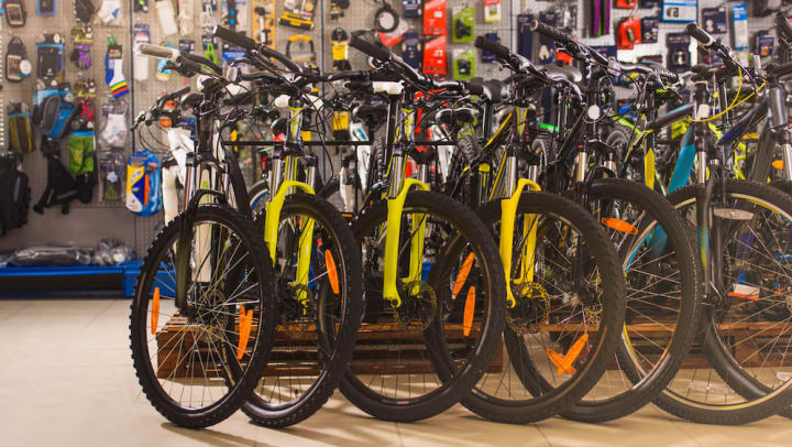 A row of colorful bikes lined up in a bike shop with a wall of tools behind them