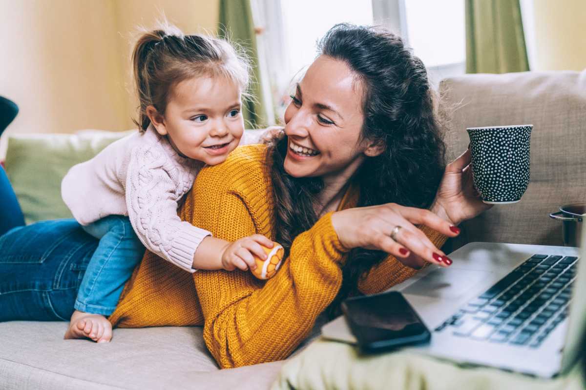 Resident woman working in her laptop in the bedroom at Murano at Three Oaks in Fort Myers, Florida