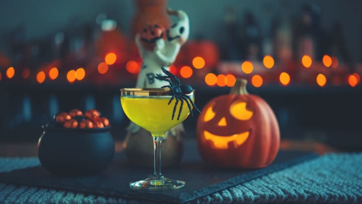 A caldron of candy, a vibrant green colored drink, and a pumpkin