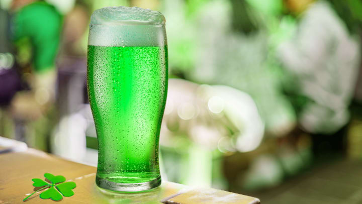 Glass of green beer on a table in a pub during the celebration of St. Patrick