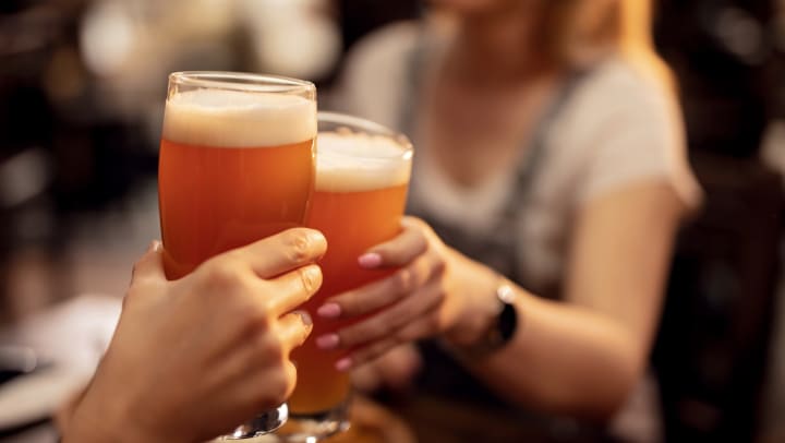 Close up of a couple toasting with lager beer.