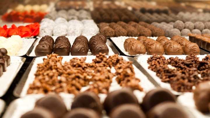 Chocolate-dipped candy and truffles sitting on display behind a glass case.