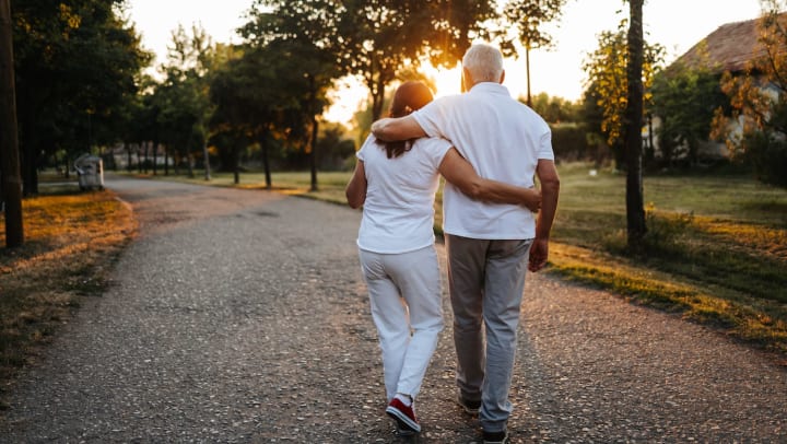 Cheerful senior couple walking in a public park at sunset