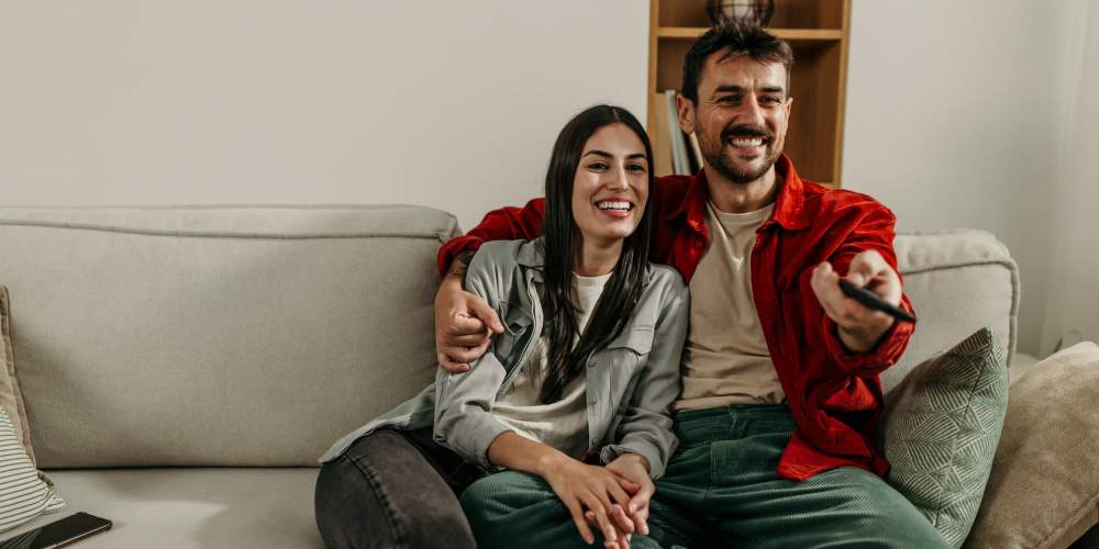 Resident couple watching movie in their living room at Panorama at Arvada Ridge in Arvada, Colorado