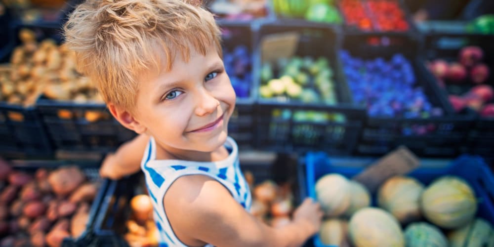 A child standing in front of fresh produce in a store near Villas at Princeton Lakes in Atlanta, Georgia