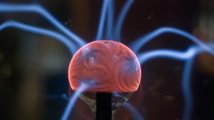A closeup of a glowing red Tesla coil with small arcs of electricity visible | Jacksonville Museum of Science & History