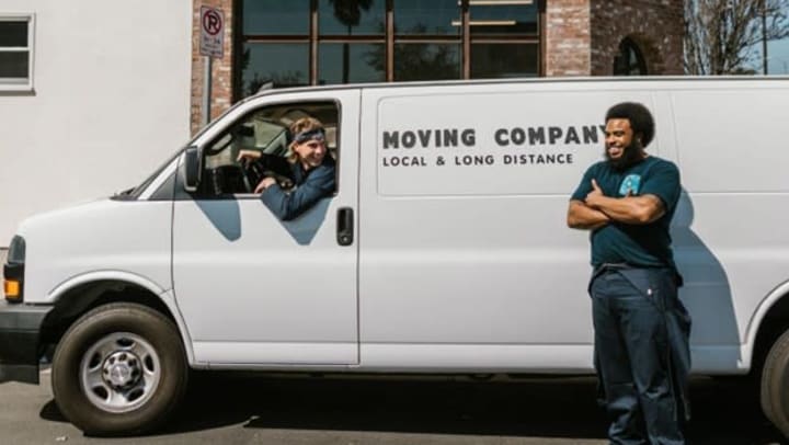 White moving van with driver and man leaning against van | Pexels