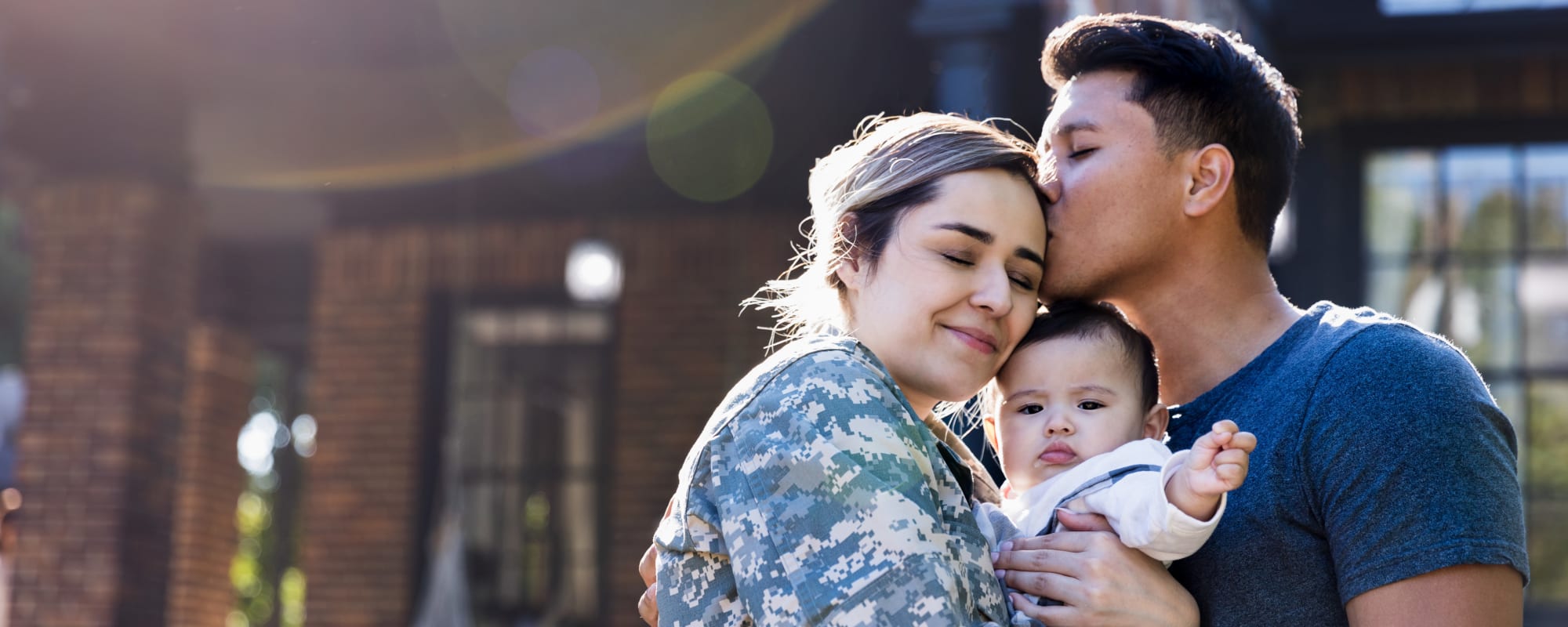 A military family embracing outside at The Village at Serra Mesa in San Diego, California