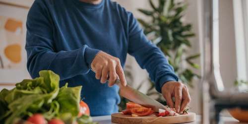 Resident chopping vegetables on a white countertop in the kitchen at Reidy Creek Apartments in Escondido, California