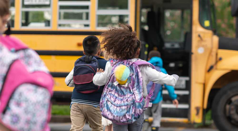 Resident children running joyfully towards their school bus near Stadium West Apartments in Arlington, Texas