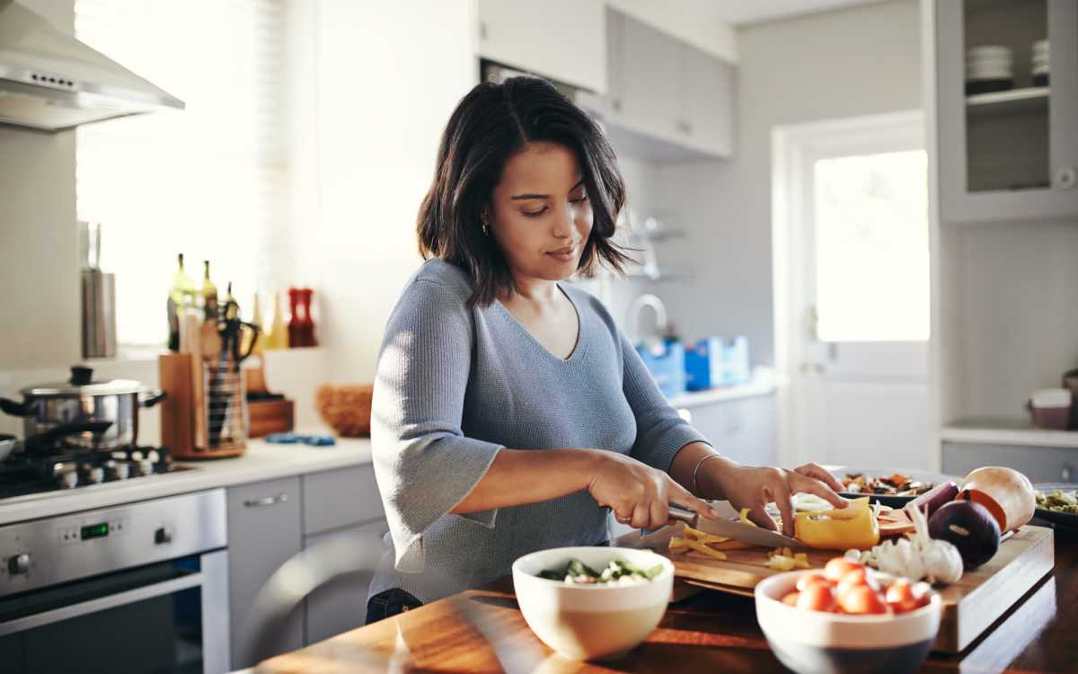Resident woman preparing meal in her kitchen at The Acacia in Palo Alto, California