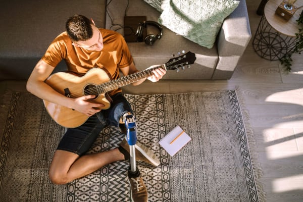 Resident playing guitar in the living room of his home at Aston Pointe in Aston, Pennsylvania