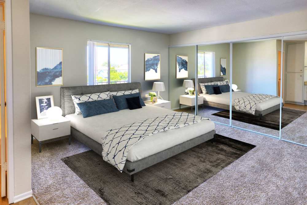 Well-lit master bedroom with large window and closet at Windwood Apartments in West Covina, California