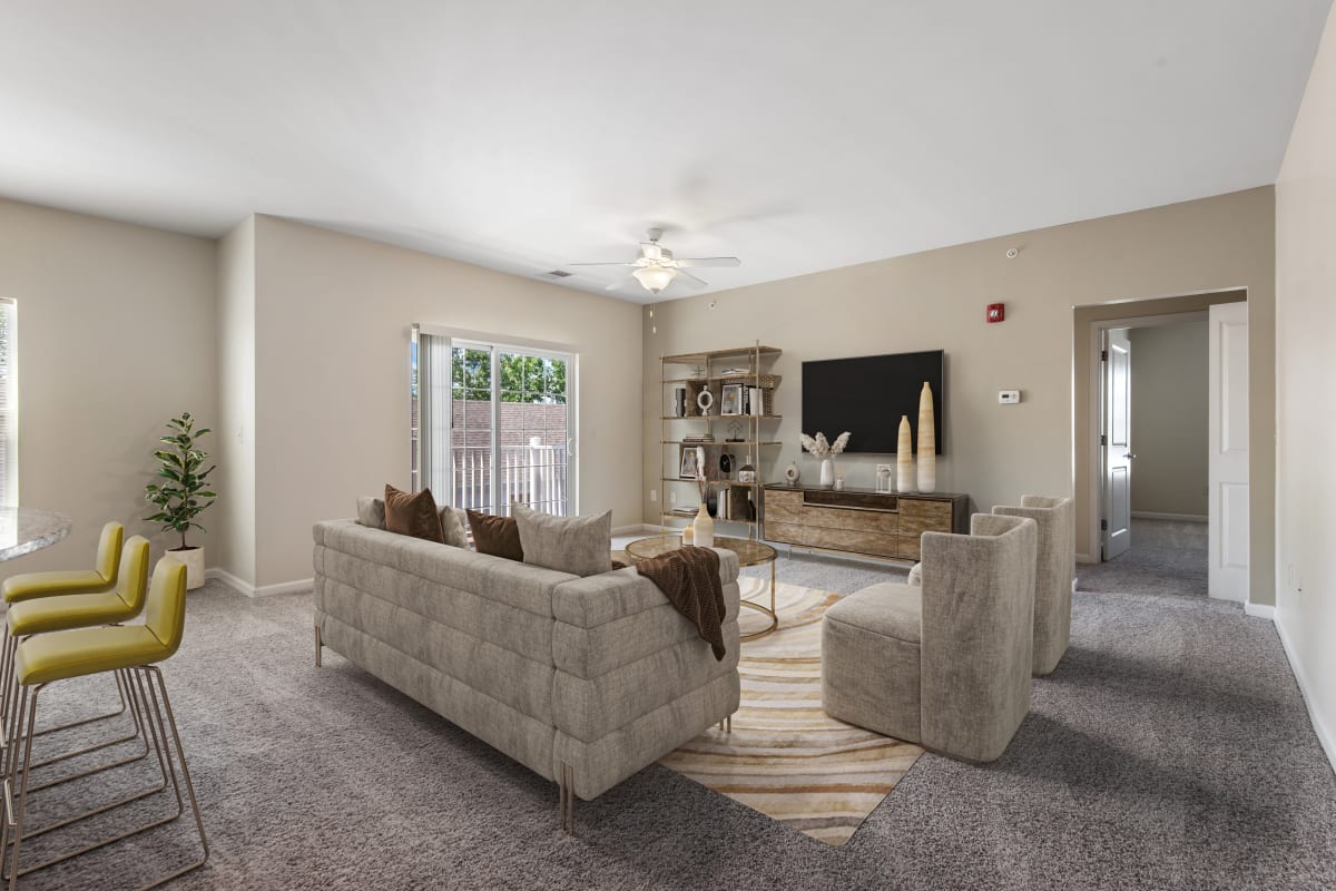 Staged living room with wall to wall carpeting and a sliding door to a balcony