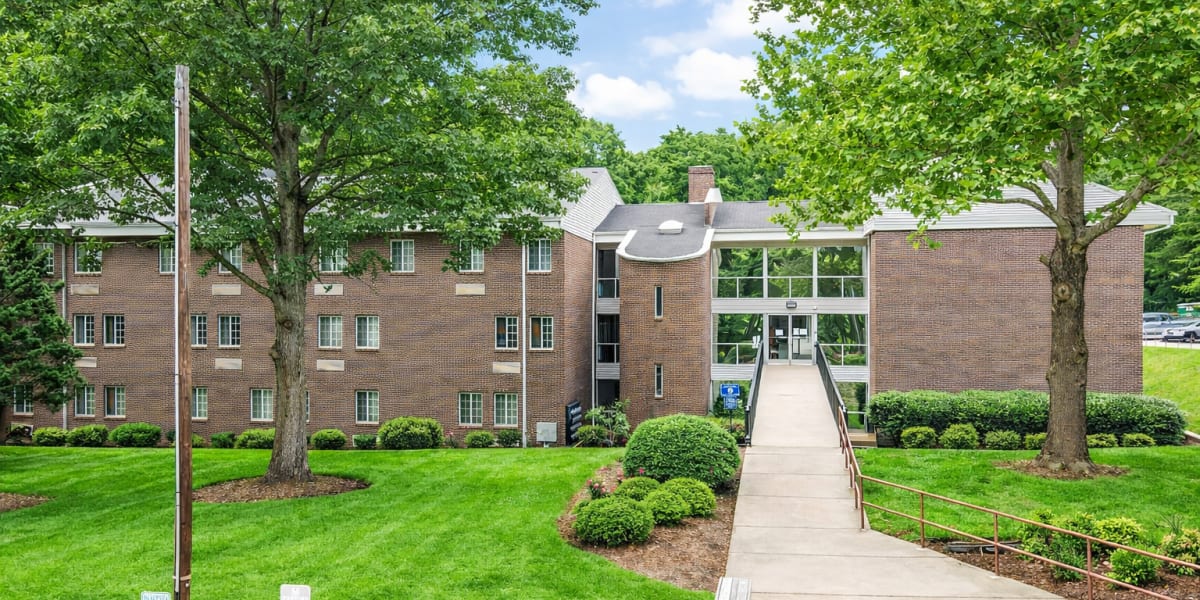 Building exterior with landscaped walkway at Arrowhead Apartments in Asheville, North Carolina