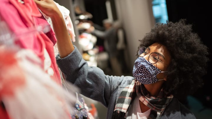 Woman wearing a mask, shopping for clothes.
