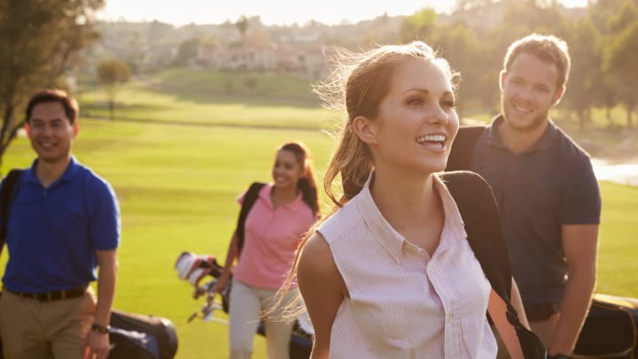 Group of young golfers smiling and walking toward the camera in San Diego, California near Olympus Corsair