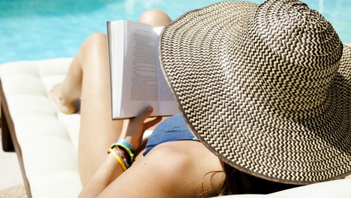 Woman enjoying a book by the pool at Olympus Steelyard in Chandler, Arizona