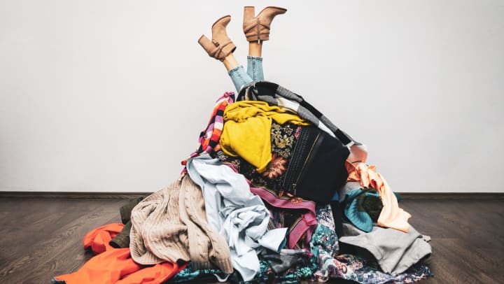 A woman’s legs stick out from the top of a huge pile of clothes.