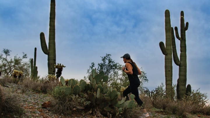 Woman hiking on a trail with saguaro cacti in the background