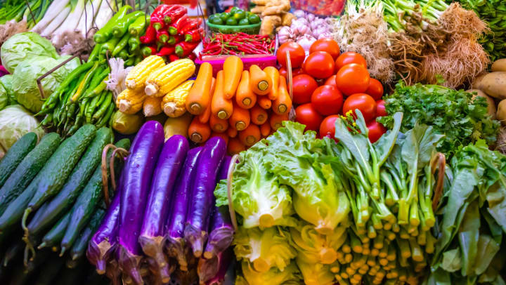 A produce stand with a selection of colorful vegetables including carrots, lettuce, tomatoes, green onions, and peppers
