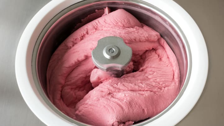 Homemade raspberry ice cream churning in a small ice cream machine.