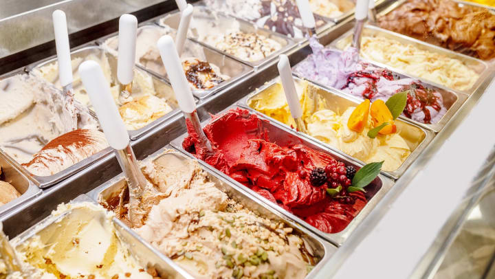 Various flavors of ice cream displayed behind glass in a dessert shop.