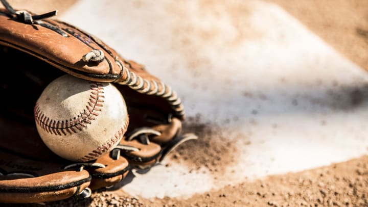 A baseball inside a baseball glove sitting atop home plate
