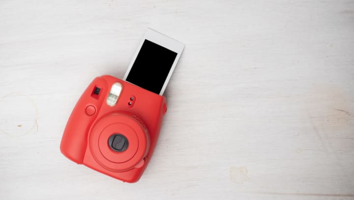 Red instant camera with blank film coming out