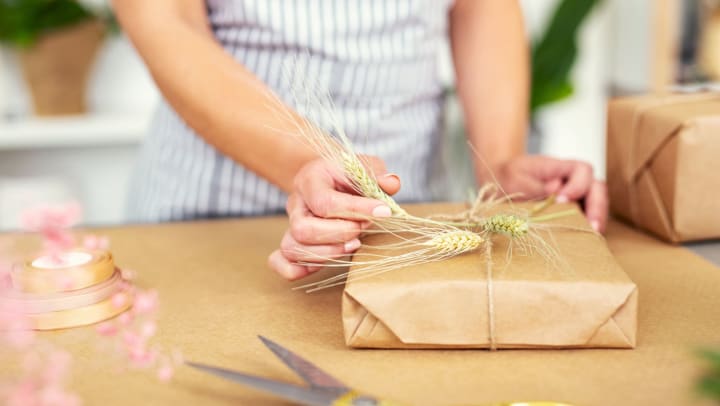 Woman standing at a desk in a shop, decorating a present