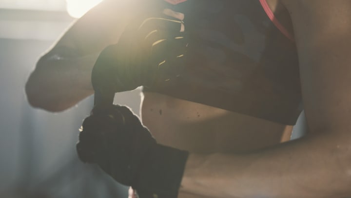 A young woman wearing workout clothes tightening her training gloves 
