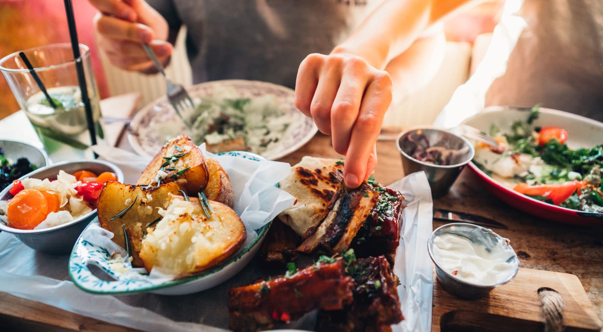 A Hand Grabbing Some Food from a Table with Several Food Dishes at 1221 Vallejo Apartments in Novato, California
