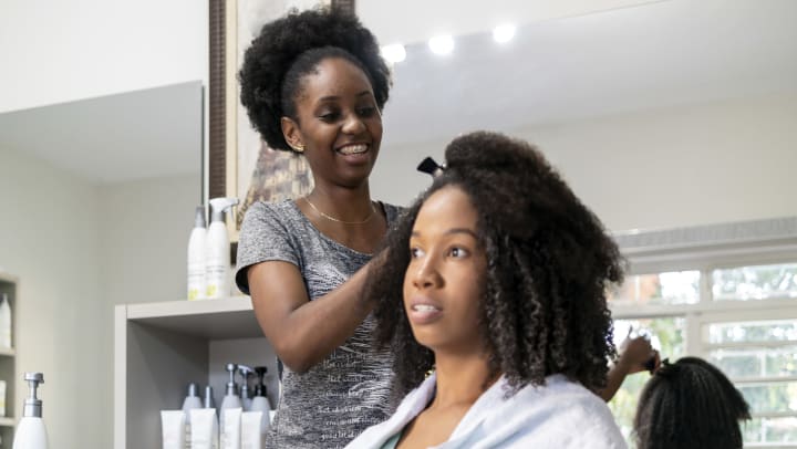 A smiling hair stylist clips a client